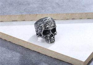 Detailed view of a vintage silver skull ring with intricate floral relief carvings