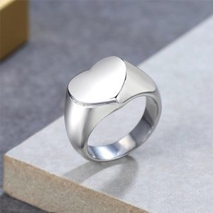 Polished silver heart shaped signet ring in stainless steel on stone background