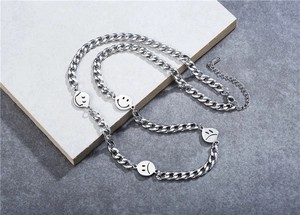 Detail view of silver titanium steel necklace with smile and cry face charms on stone base