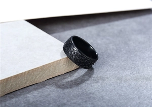 Detalle de anillo de acero de titanio negro con motivos vikingos sobre bloque de piedra