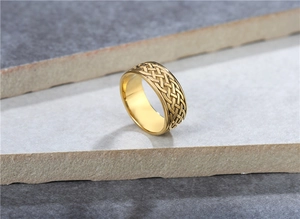 Detalle macro de anillo vikingo dorado con nudo celtico sobre fondo de piedra gris