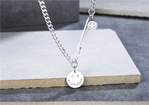 Détail du collier à maille gourmette en acier titane argenté avec pendentifs sourire
