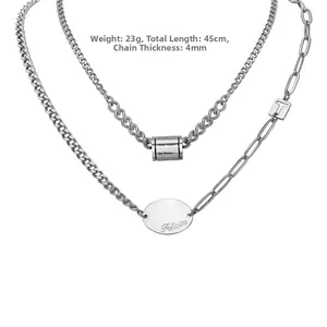 Detail of double-layer stainless steel necklace with engraved oval tag and cube pendant