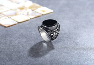 Macro detail of vintage silver men's ring with black stone and fleur-de-lis carving
