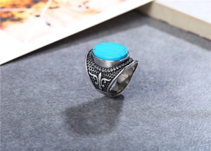 Macro view of vintage titanium steel ring with turquoise stone and fleur-de-lis detail