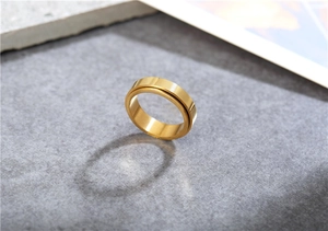 Macro shot of polished gold-tone spinner ring on a textured grey stone background