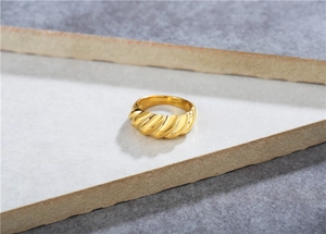 Macro view of gold croissant dome ring with twisted metal texture on stone base