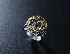 Macro d'une bague crâne punk avec accents dorés et yeux en pierres vertes sur fond sombre