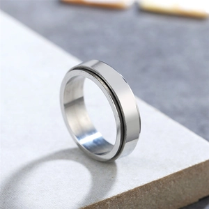 Minimalist silver titanium steel spinner ring with black groove on a stone pedestal