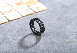 Macro detail of matte black stainless steel Cuban link ring on a textured surface