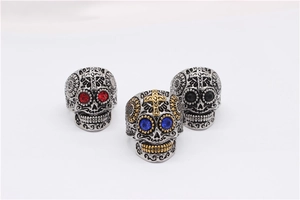 Détail de trois bagues tête de mort mexicaines avec yeux en pierres colorées et gravures