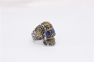 Gros plan sur bague tête de mort gothique avec yeux en gemme bleue et détails dorés