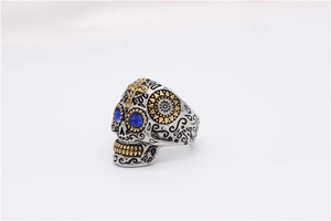 Gros plan détaillé d'une bague tête de mort punk avec gemmes bleues et touches dorées