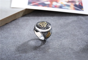 Detailed shot of retro Viking Valknut ring with gold runes on a rugged stone surface