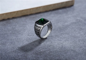 Detailed macro view of square green gemstone on vintage silver steel ring with leaf pattern