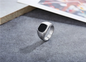 Detalle macro de un anillo de sello para hombre en acero plateado con piedra negra cuadrada