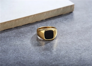 Detalle de un anillo de titanio dorado con una piedra negra cuadrada pulida incrustada