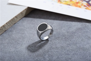 Close-up of silver steel signet ring featuring a flat round black enamel inlay surface
