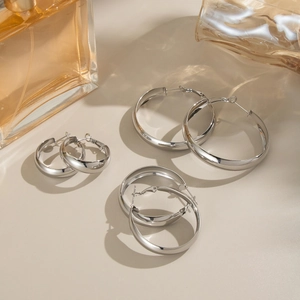 Detailed view of three pairs of chunky polished stainless steel hoop earrings set