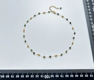 Detail of beaded emerald green natural stone necklace with gold metal beads and lobster clasp