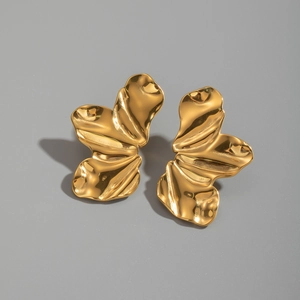 Détail de boucles d'oreilles en acier doré au design organique et vagues irrégulières