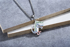 Détail d'un pendentif dinosaure blanc avec graffitis colorés et chaîne en acier