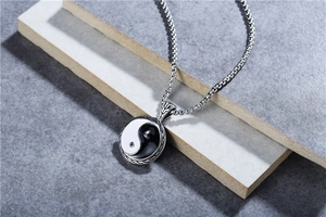 Detailed shot of Tai Chi Yin Yang pendant with woven metal frame and steel box chain