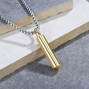 Gold cylinder perfume pendant with silver box chain on grey stone background