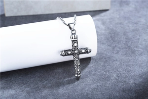 Close-up of retro silver cross pendant with vintage engraving on a square bead chain