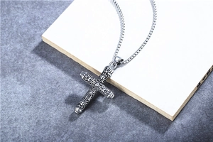 Macro detail of retro stainless steel cross pendant with intricate embossed patterns