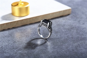 Detailed close-up of a vintage men's steel ring with square black stone and vine engravings