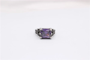Detailed macro view of a vintage silver ring with a large square purple gemstone and filigree