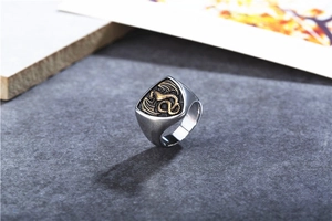 Macro detail of men's stainless steel ring featuring a golden dragon crest on shield