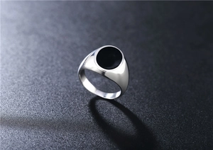 Macro detail of men's silver stainless steel signet ring with black round enamel inlay
