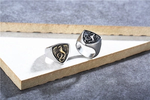 Detailed close-up of shield-shaped stainless steel rings with dragon relief carvings