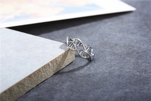 Macro detail of high-polish silver DNA double helix ring on minimalist stone display
