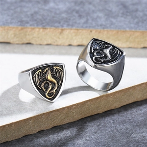 Gothic dragon shield signet rings in silver and gold finish on stone background