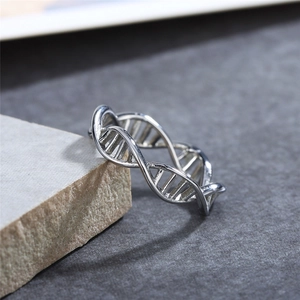 Polished silver DNA double helix ring with intricate cutout details on a stone base