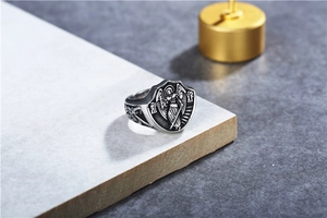Gros plan d'une bague chevalière en argent vieilli avec ange et motifs religieux
