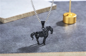 Dettaglio del ciondolo a forma di cavallo nero vintage su catena d'argento e sfondo di pietra