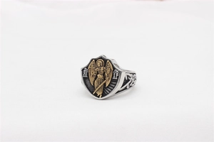 Gros plan d'une bague bouclier argentée avec relief d'Archange doré et motifs celtiques