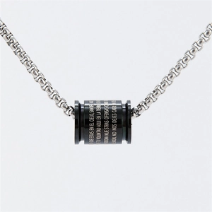 Macro detail of black cylindrical pendant with laser engraved Spanish religious scripture