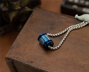 Macro view of blue stainless steel cylindrical pendant with engraved Spanish prayer