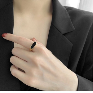 Minimalist gold titanium ring with black oval shell inlay worn by model in black suit