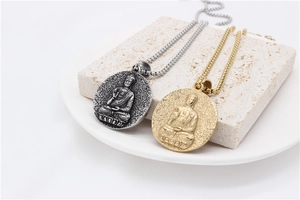 Dettaglio dei ciondoli con rilievo di Buddha in oro e argento vintage su una pietra decorata
