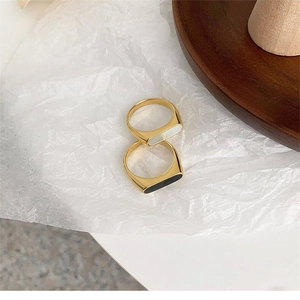 Detail view of geometric gold rings with white shell and black enamel inlays on paper