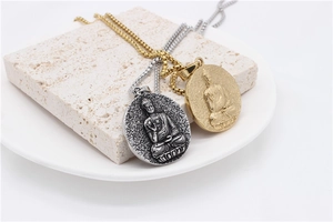 Dettaglio dei ciondoli Buddha in rilievo in argento e oro su pietra ruvida