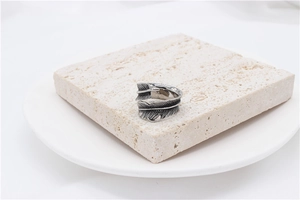 Macro detail of retro feather ring with vintage oxidized texture on travertine stand
