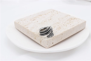 Close-up of vintage silver feather ring with detailed textures on stone surface