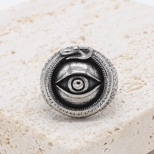 Vintage stainless steel ring featuring All-Seeing Eye and Ouroboros on stone surface